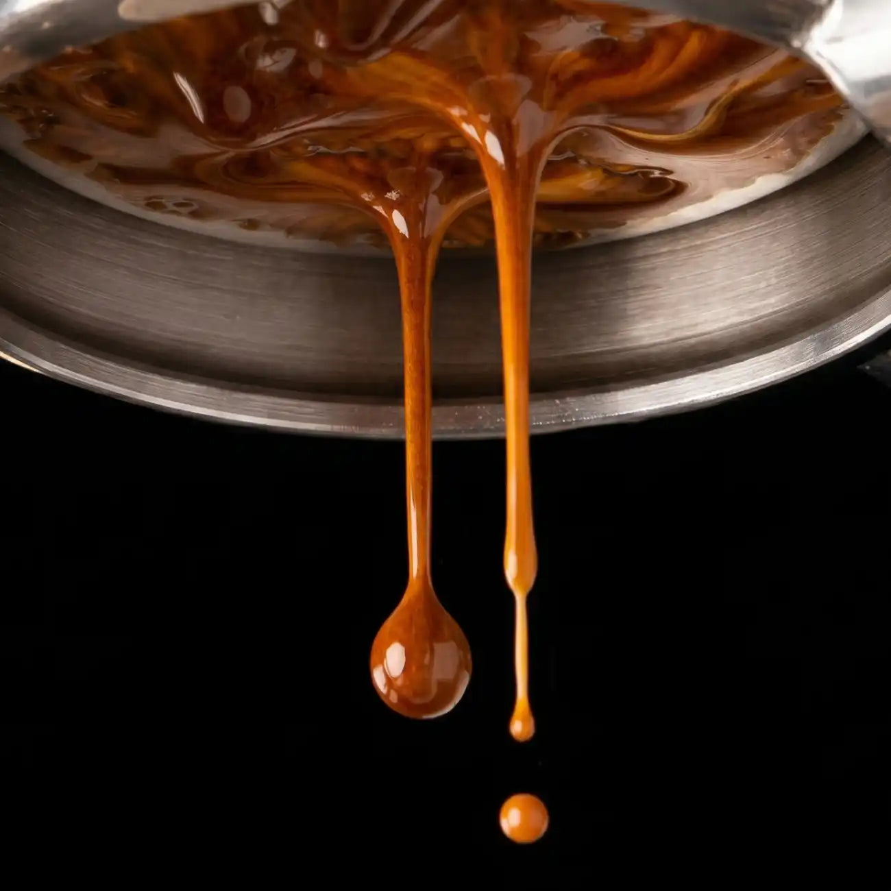 Nahaufnahme eines bodenlosen Siebträgers, aus dem cremiger Espresso von diekleinebohne.de mit schöner Crema tropft
