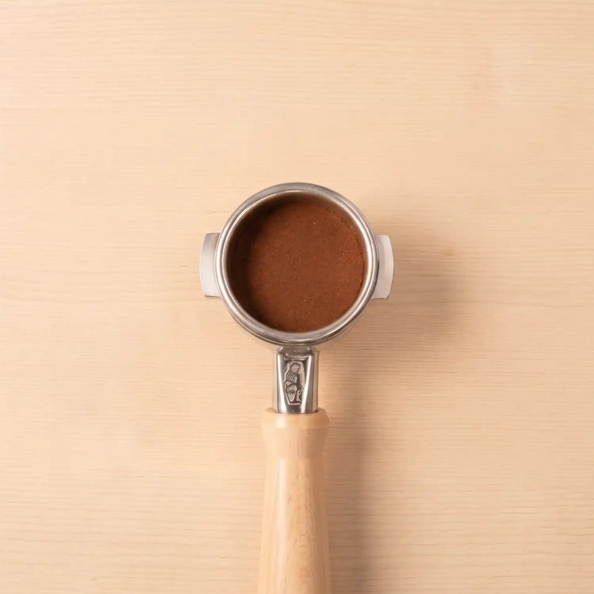 La Marzocco Siebträger mit gemahlenem Specialty Coffee auf einem Hintergrund aus hellem Holz
