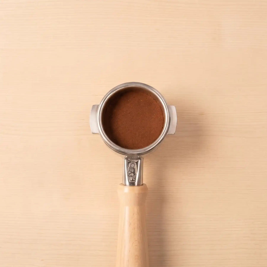 La Marzocco Siebträger mit gemahlenem Specialty Coffee auf einem Hintergrund aus hellem Holz